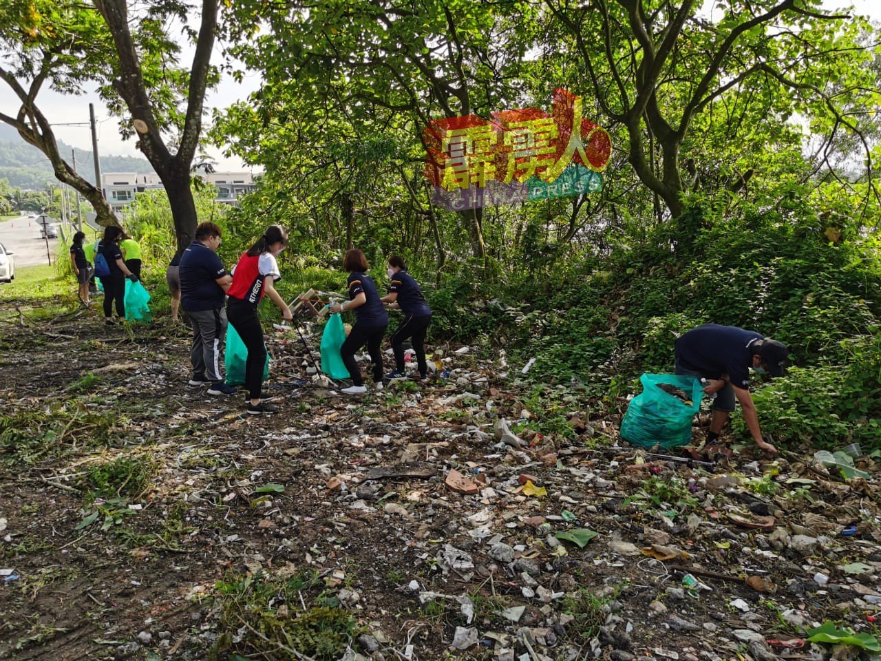 热心团员及居民联手清理路边的垃圾，还该区清洁环境。