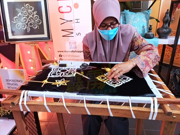 这名妇女在现场示范马来传统金线刺绣。