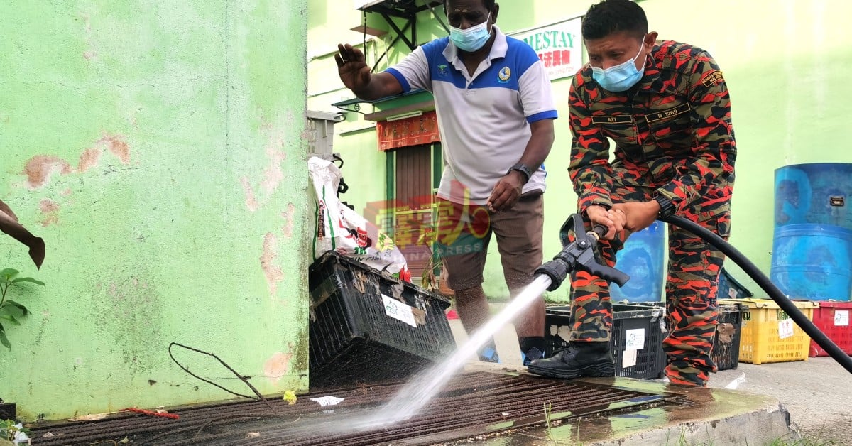 消拯员以强力水冲洗蚊症热区店屋週遭的阻塞水沟。