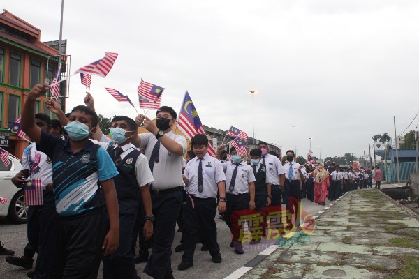 游行队伍沿途挥舞国旗、高喊“默迪卡”口号。