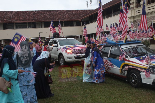 挂满国旗的宝腾轿车及1辆货卡，吸引师生前来拍照打卡。
