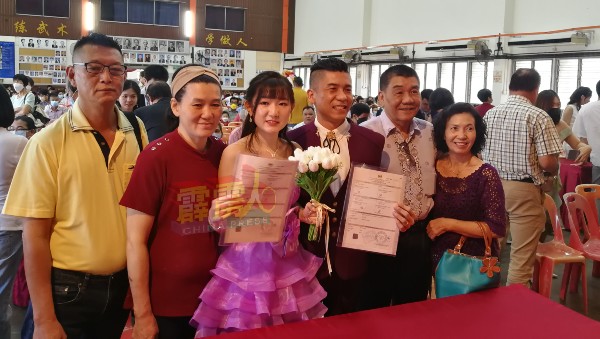 黄子豪与黄晓菁身穿紫色的婚服，在双方父母陪同下，签下一纸婚书。