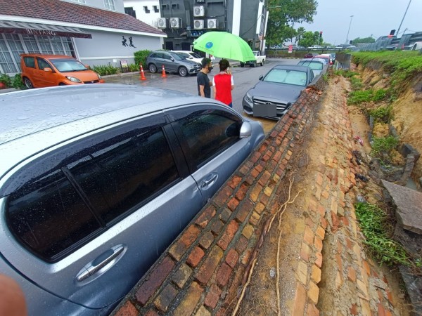 怡保南区商业区于6月18日的一场大雨，导致该处围牆倒塌，压及停泊在该处的一些轿车。（档案照）