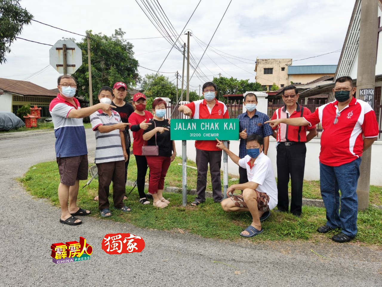 林瑞发（左6起）、陈根城、刘新泉、刘炳金（蹲者）及村民，指着瓜拉光村民自费自製的“赤溪路”牌，是该村的“地标”。
