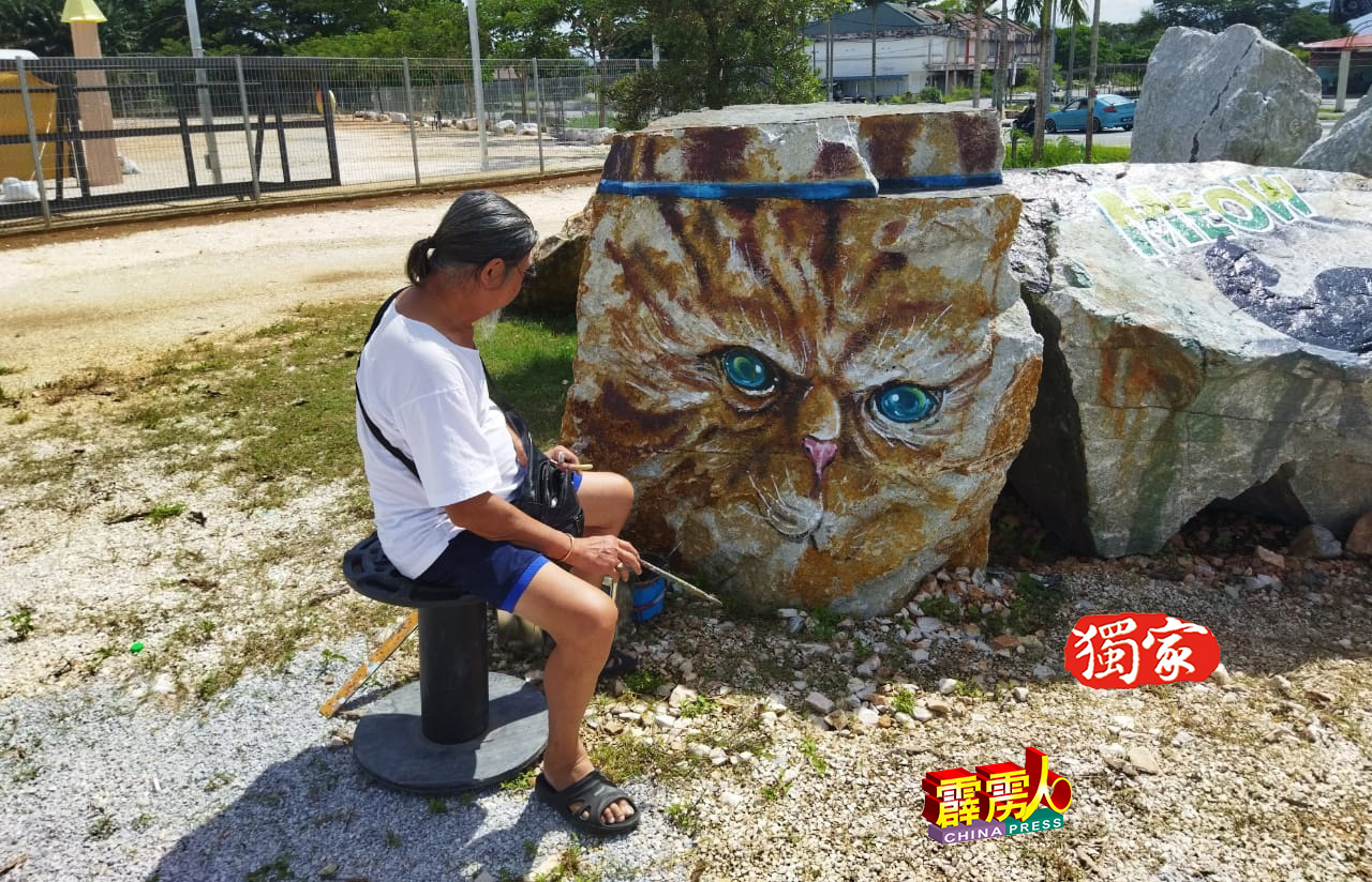 李朝俊正在石头上画猫的作品，猫眼犀利。