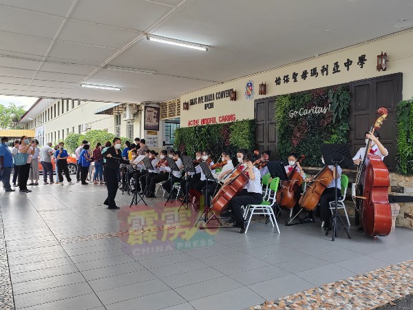该校入口处，学生们手持大、中、小提琴，演奏迎宾曲。