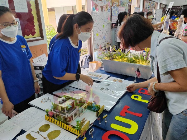 一名家长在其中一个展览摊上，了解学生所制的植物标本。