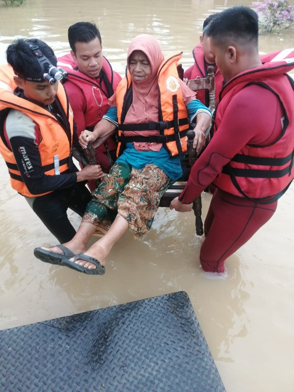 消拯员合力将行动不便的妇女，被抬上罗厘送往临时疏散中心。