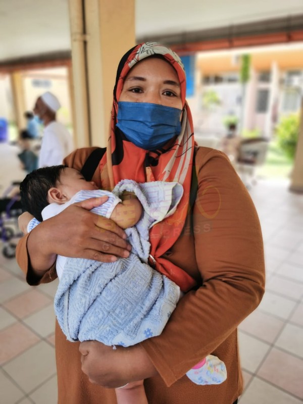 娜斯花玛抱着4个月大的孩子，在医院等候车子到来。