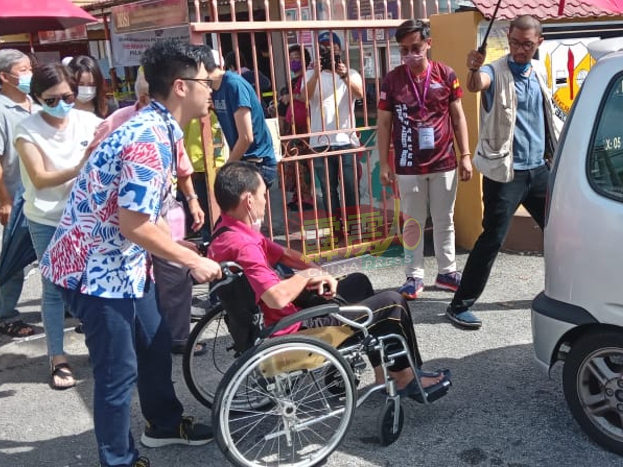希盟怡保东区候选人李存孝巡视甘榜巴西富地小学投票中心时，巧遇年迈残疾的选民，并主动趋前协助推轮椅，让老选民登上车子离开。 