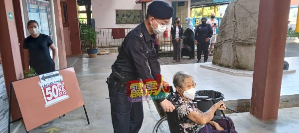 在其中一间投票中心内，怡保副警区主任李瑞式也推着坐轮椅的老者离开投票中心。