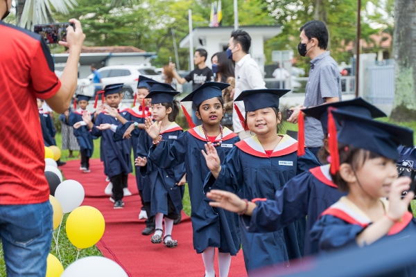 毕业生在走红毯时，开心地向家长及老师招手。