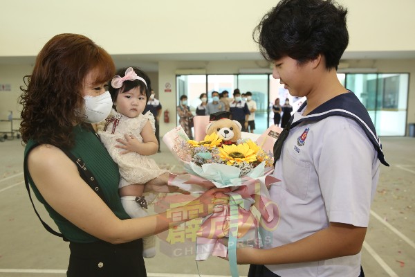 一名家长将手中的花束，赠送毕业生。