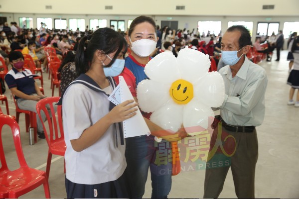家长手持大大的气球花朵，祝福子女开心毕业。