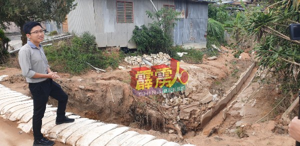 何子扬展示新村遭洪水破坏的水沟。