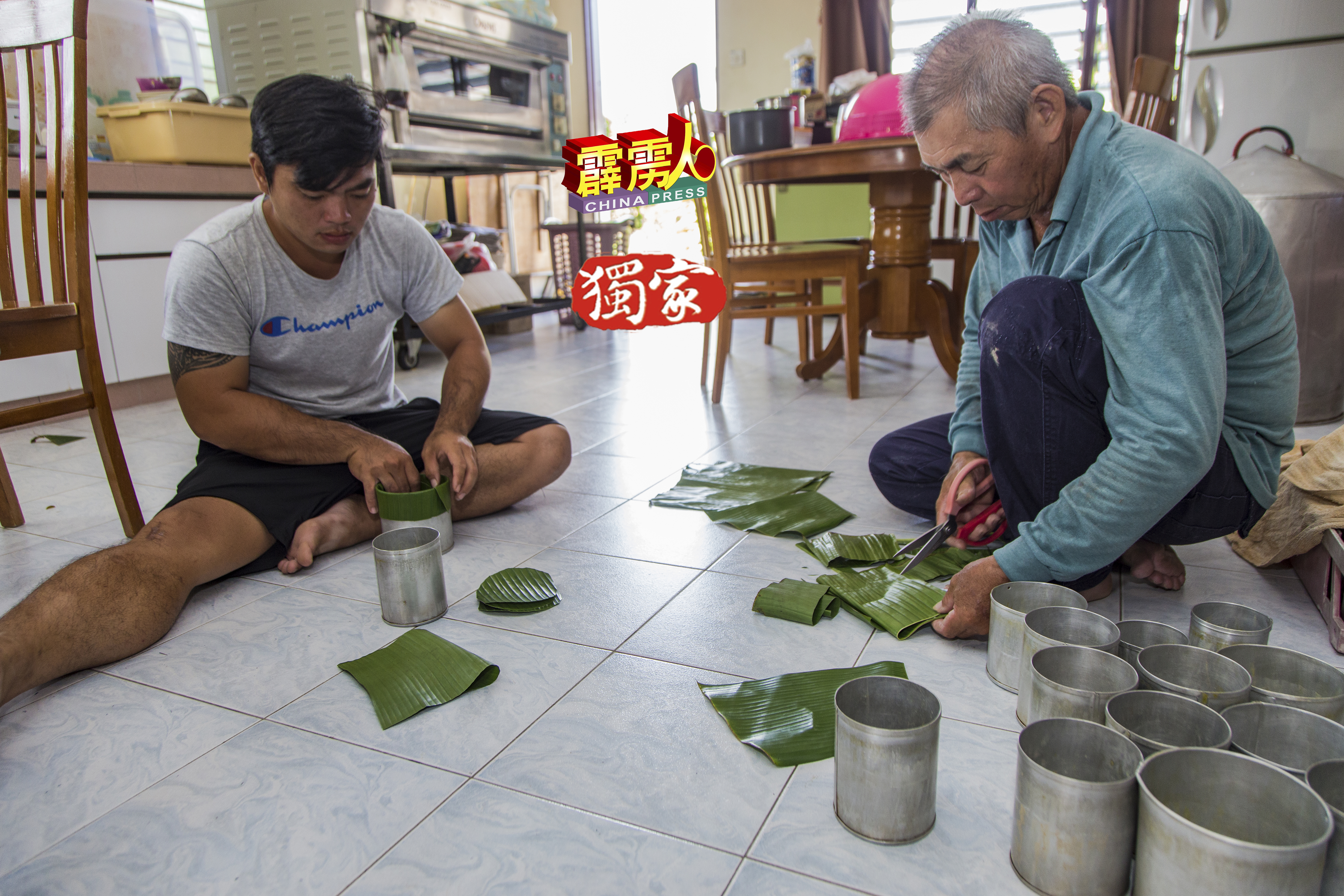 郑观福剪綵蕉叶的合适尺寸，儿子郑志豪则把蕉叶置入罐内，作为包裹年糕的外衣。