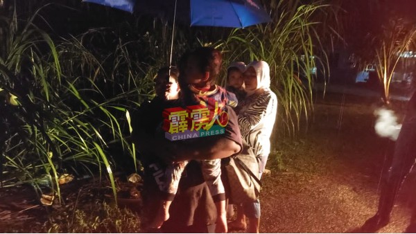 逃出灾区的灾民，抱着孩撞撑伞前往临时疏散中心。