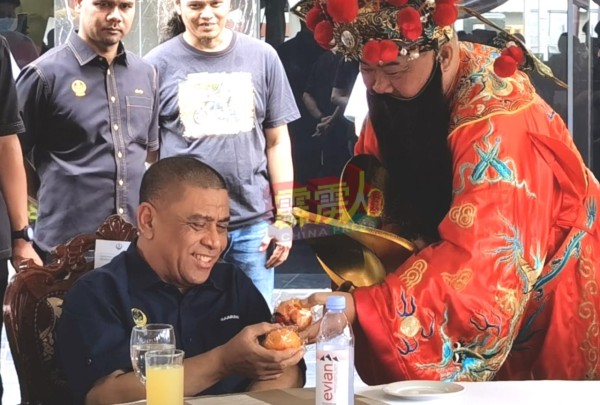 霹雳州务大臣拿督斯里沙拉尼（坐者 ）周二出席一场屋业推展礼时，欣喜接受财神爷送来的年柑。