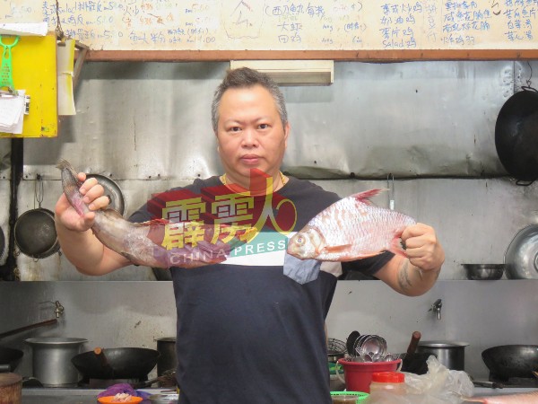 玲珑七叔饭店东主李志刚展示其饭店主打招牌菜玲珑驰名淡水河鱼。 
