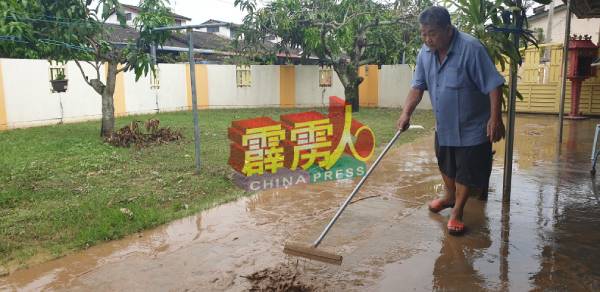张锦权忙着清理住家庭院的泥泞。