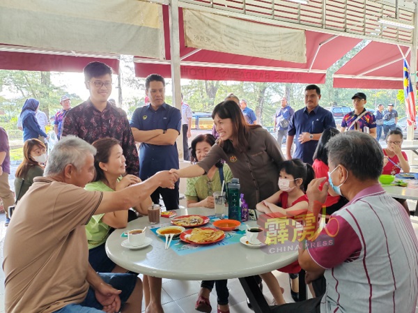 张念群（站者右起）及李存孝在派发传单时，不忘与民众交流，握手问好。