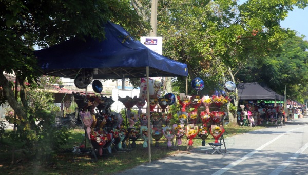 朝往拉曼大学方向道路边，有许多摆卖花束的摊位，吸引市民购买。
