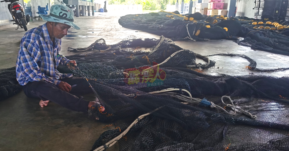 受补贴柴油固打削减影响的渔民舵手，没出海的日子唯有补网打发时间。