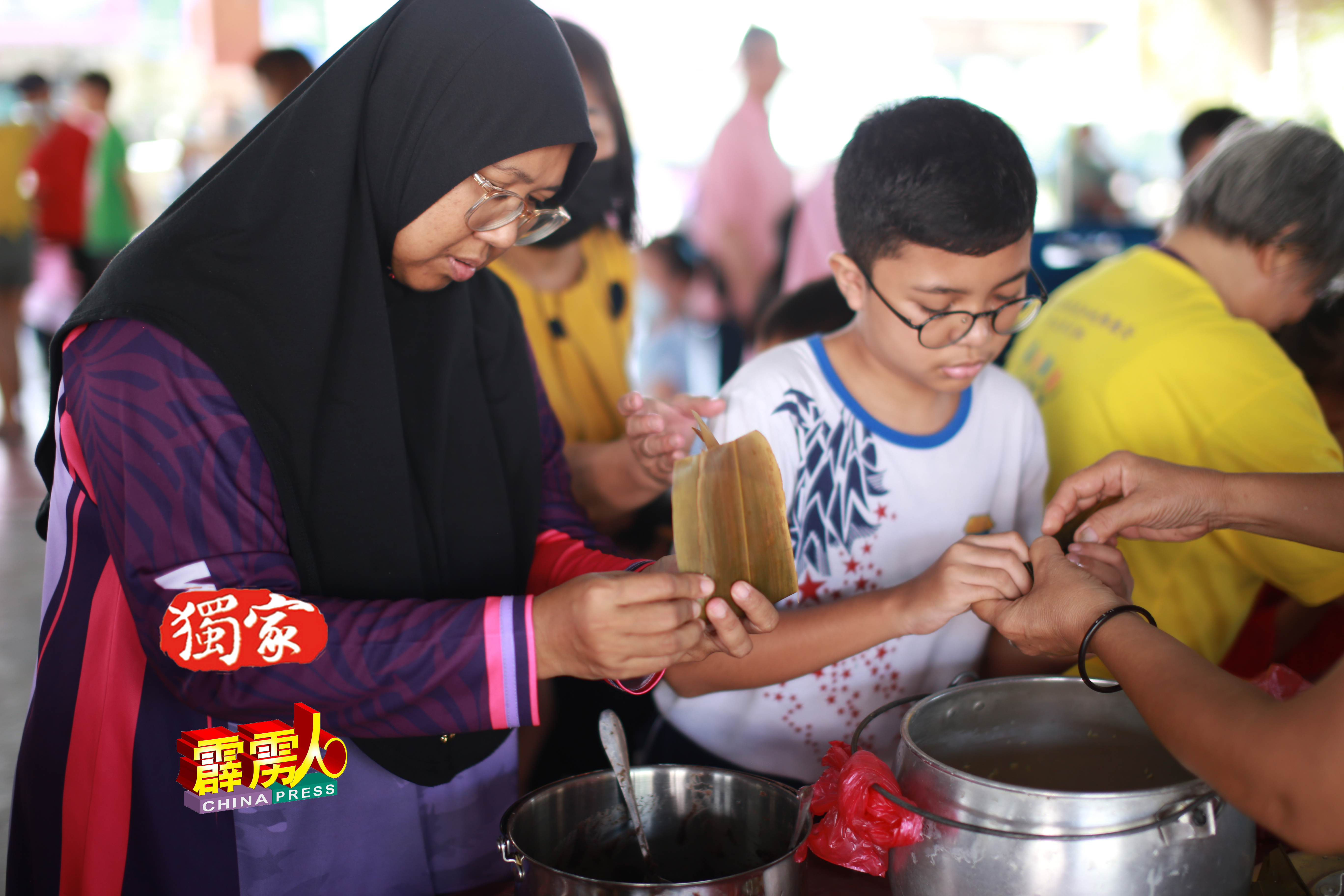 马来妇女娜扎都西玛与儿子，一起学习裹粽。