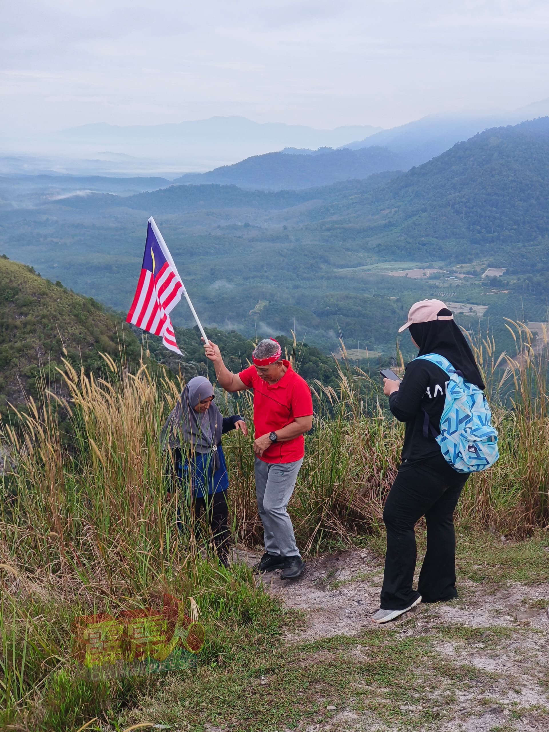 一对马来夫妇，在光头山山顶高举辉煌条纹，展现满满的爱国之心。