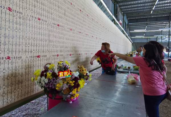 一些前来拜祭的民众，在布告板上寻找先人的灵牌以便拜祭。