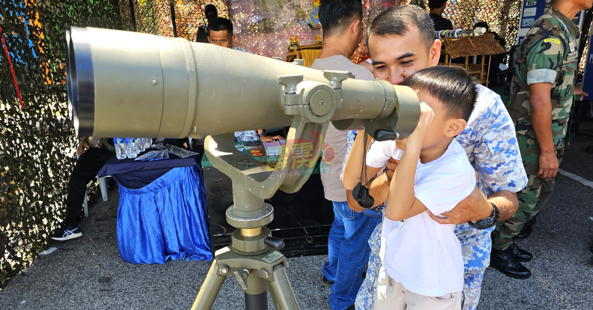 态度亲民的海军叔叔，向好奇的小孩讲解如何使用望远镜。