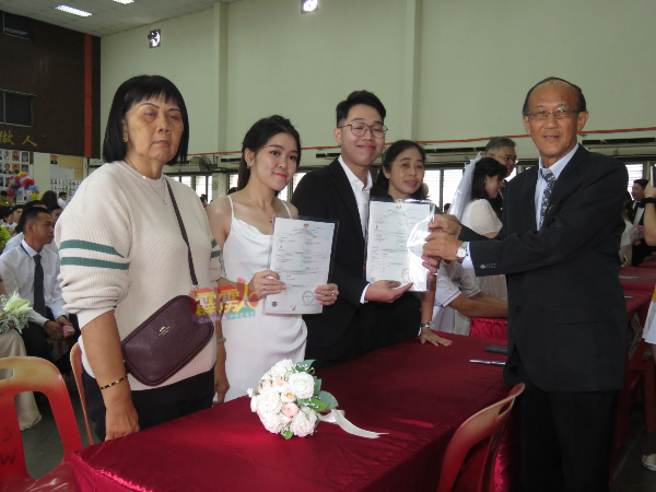 怡保中国精武体育会助理婚姻注册官吴业成（右）颁发注册结婚证书给一对新人。