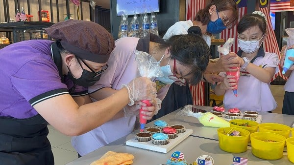 职员（左）正教导孩子如何制作与装饰杯子蛋糕。