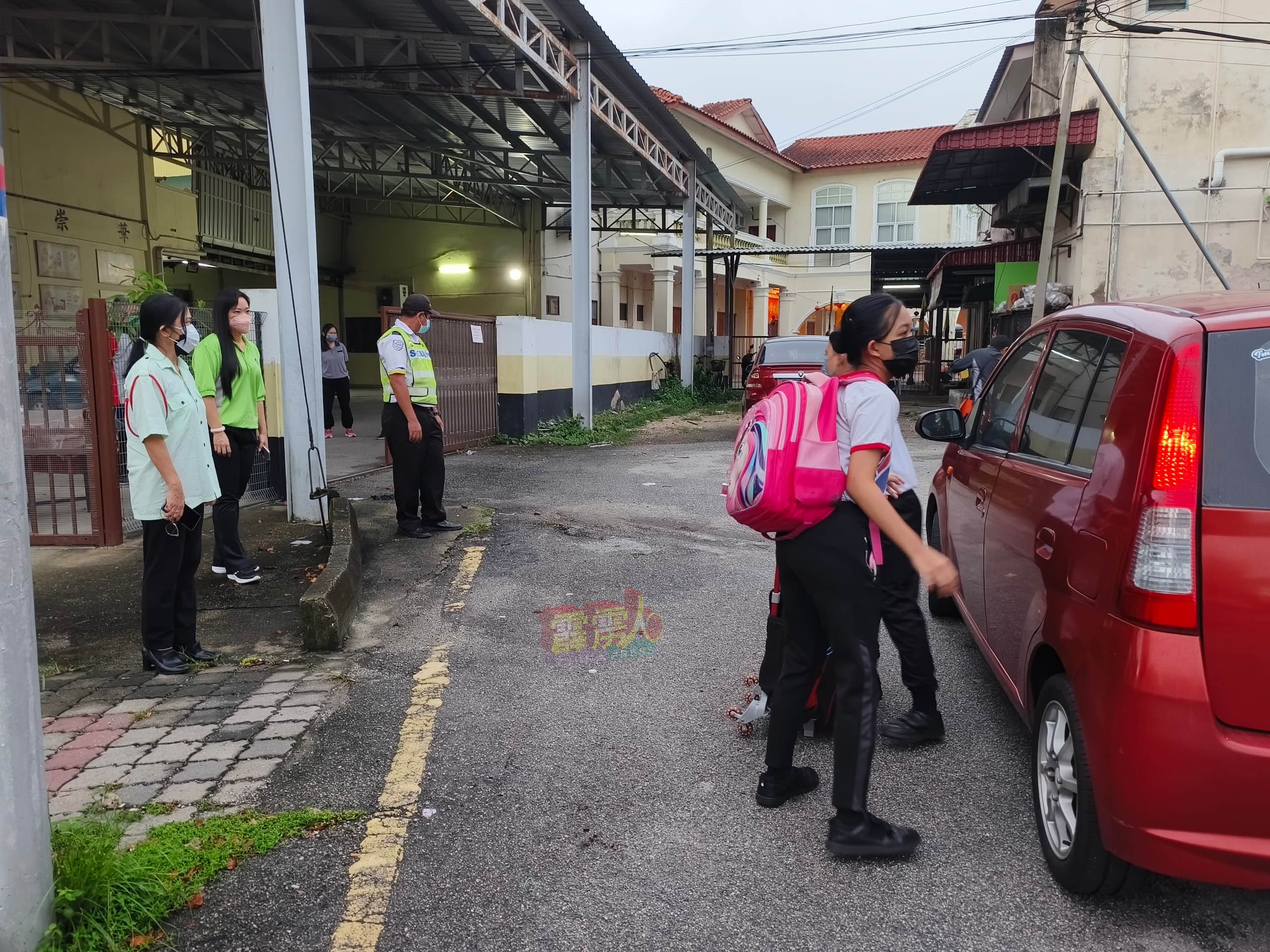 崇华小学校长林淑宝（左起）及第一副校长冼慧珊，在学校侧门（悦来茶室后面）看守，确保復课学生都有做足安全措施。