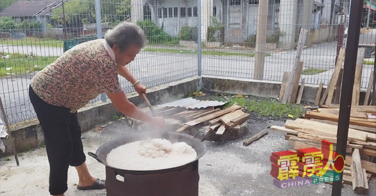 昔日女矿工刘女士用长锅铲翻动煮好的饭，用大锅煮出来的饭，份量十足。
