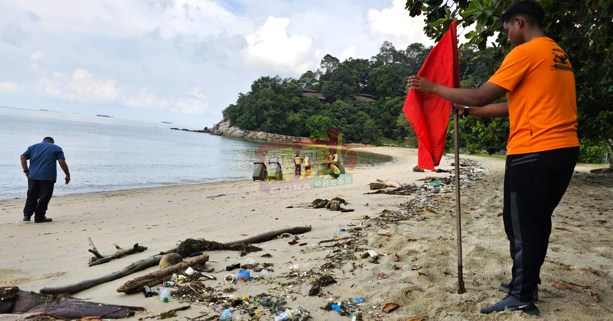 驻守在直落迪海滩的民防部队队员，在海滩树立红色旗帜，暂时禁止游客下水。