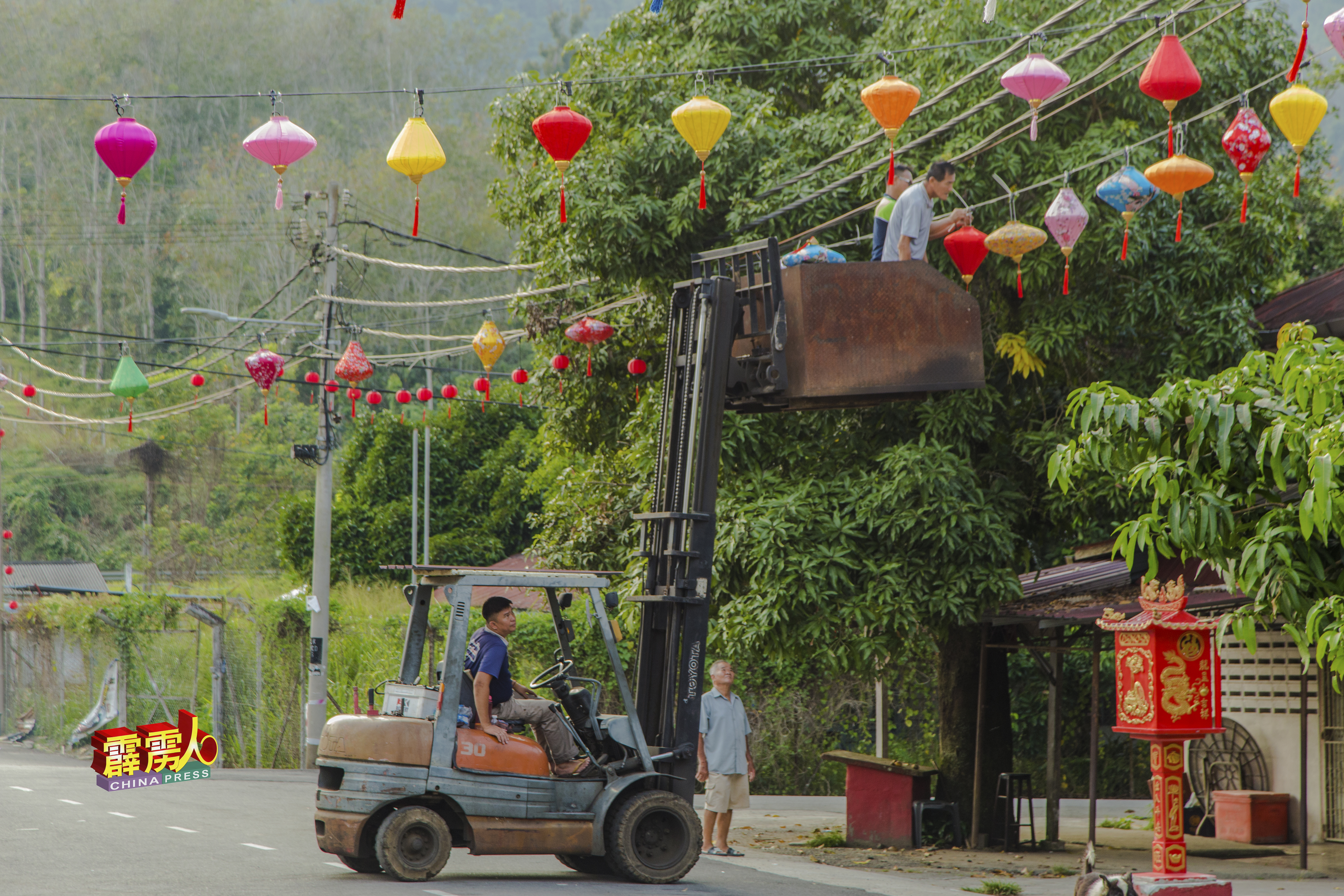 热心村民卢泇新出动起重机，让村委挂上七彩缤纷的越南灯笼。