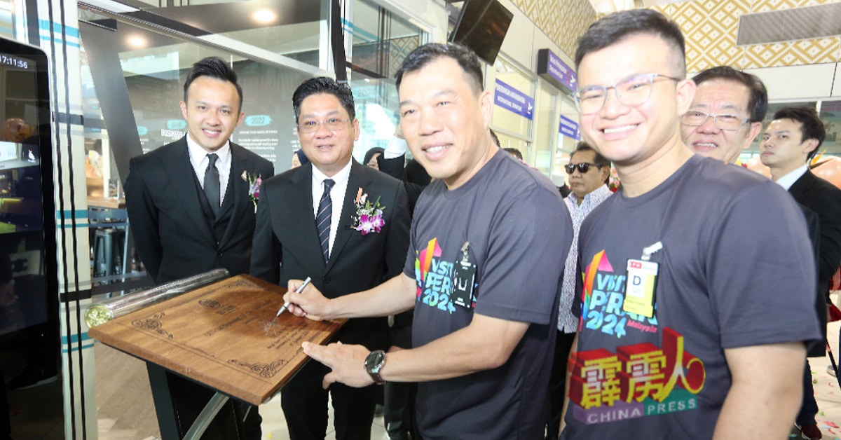 罗思义（右2）在CM Deli Lounge餐厅餐厅的宣传板上签名。左起为蔡义伟、黄玉升和张迪翔。