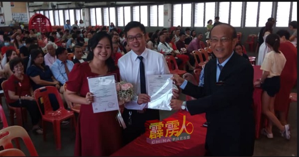 吴业成（右）颁发结婚证书给一对新人赵彩云（左）及洪康明。
