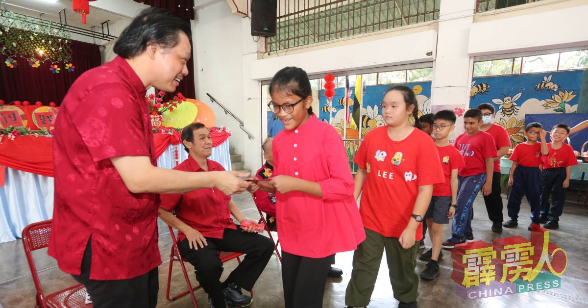 学生们从长辈手中接过压岁钱，寓意新的一年健康平安。左起为曾敏凯和祝武兴。