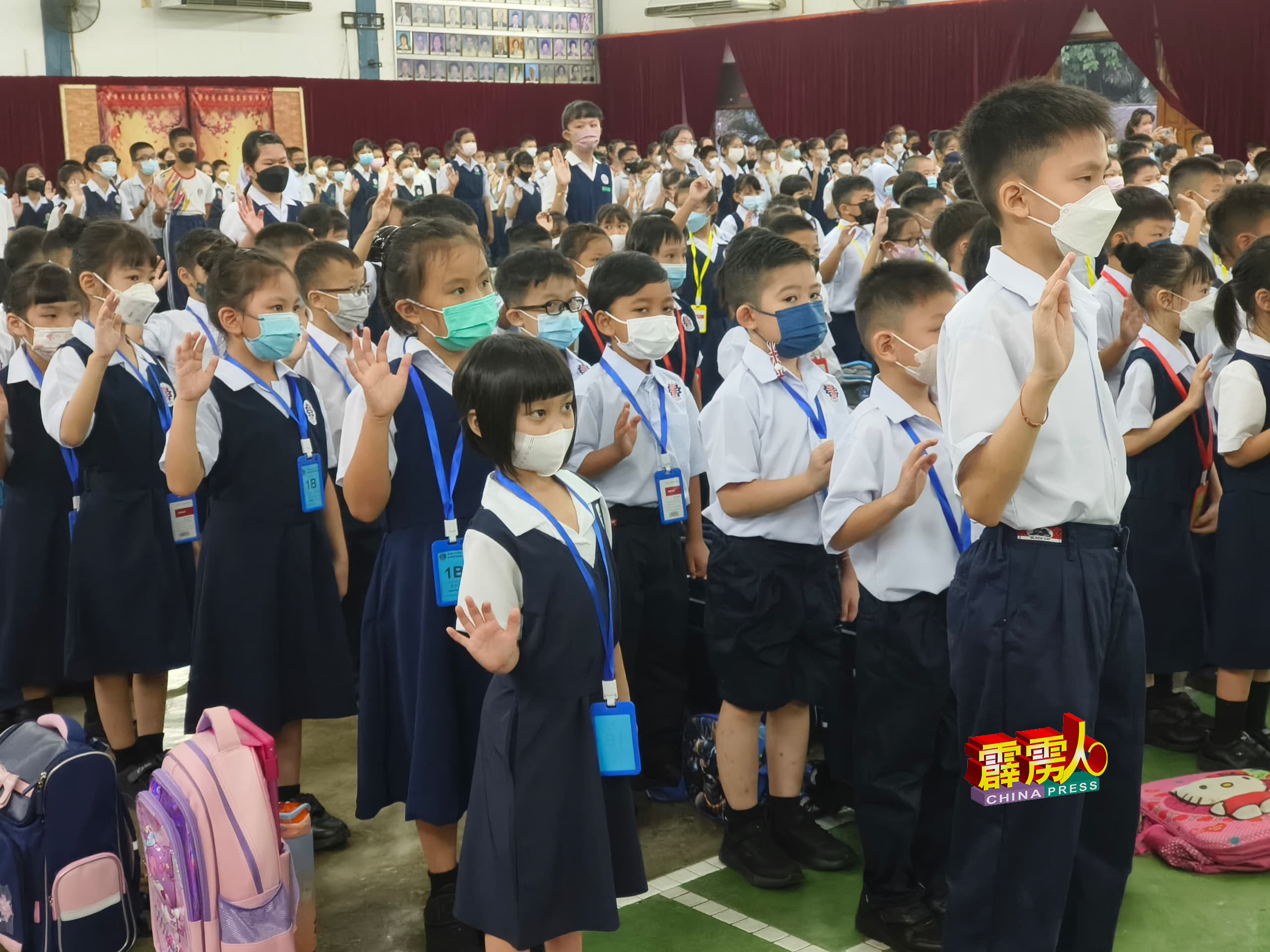 学生们在开学礼上，举起右手宣誓。