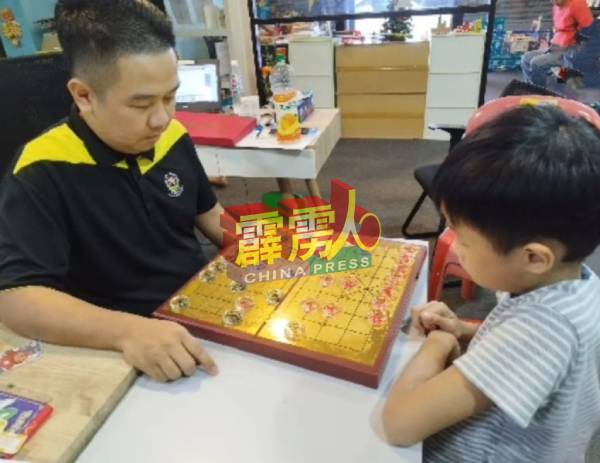 徐建兴（左）与儿子徐佳灏（右）下棋，通过布局、布防和对弈，激发孩子的思维。