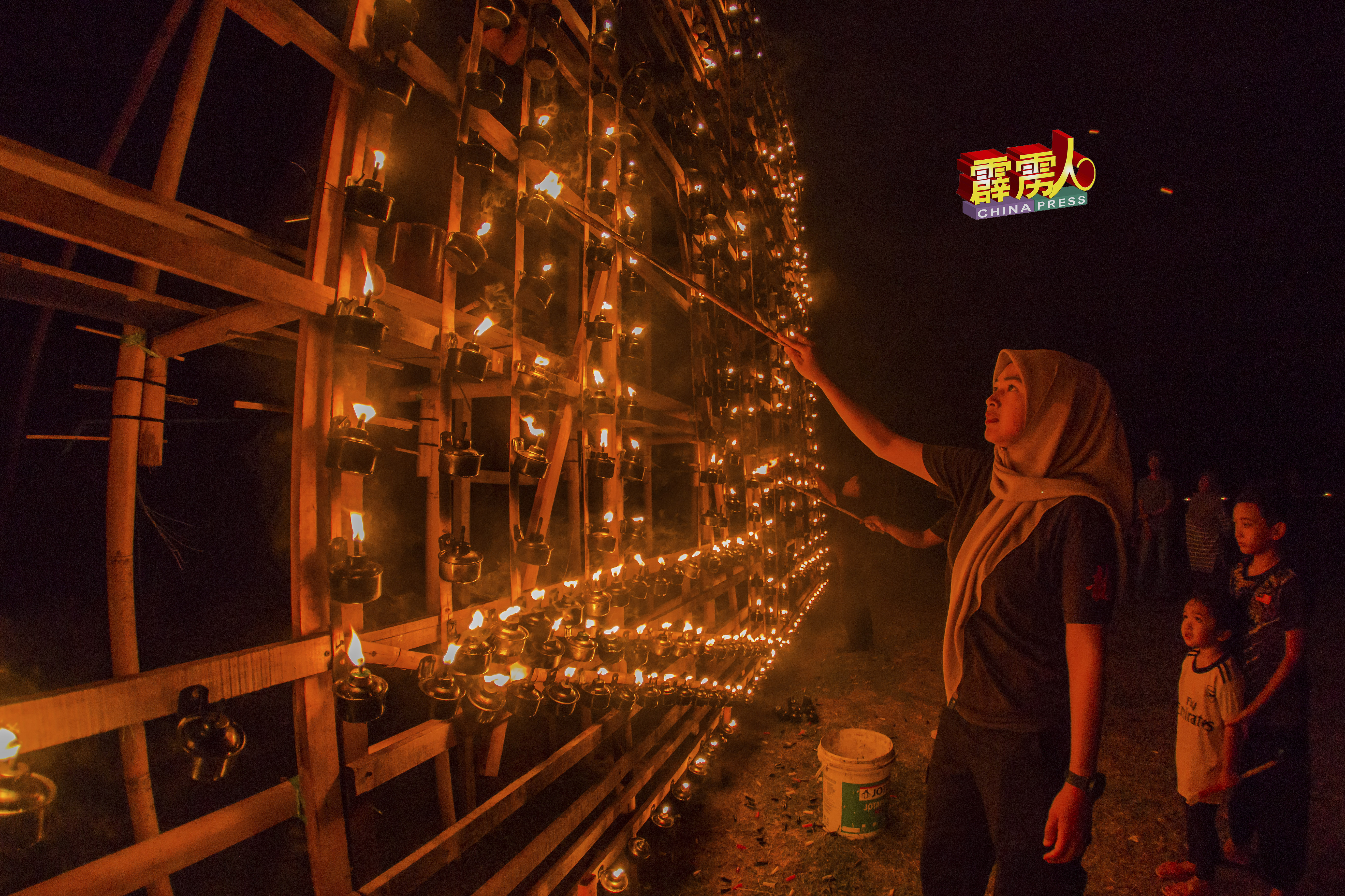 女村民协助点燃土油灯，让大家看见甘榜立布最美的一面。