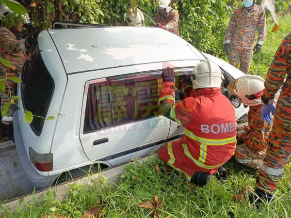 消拯人员向卡在沟上的轿车施援手，救出女司机。