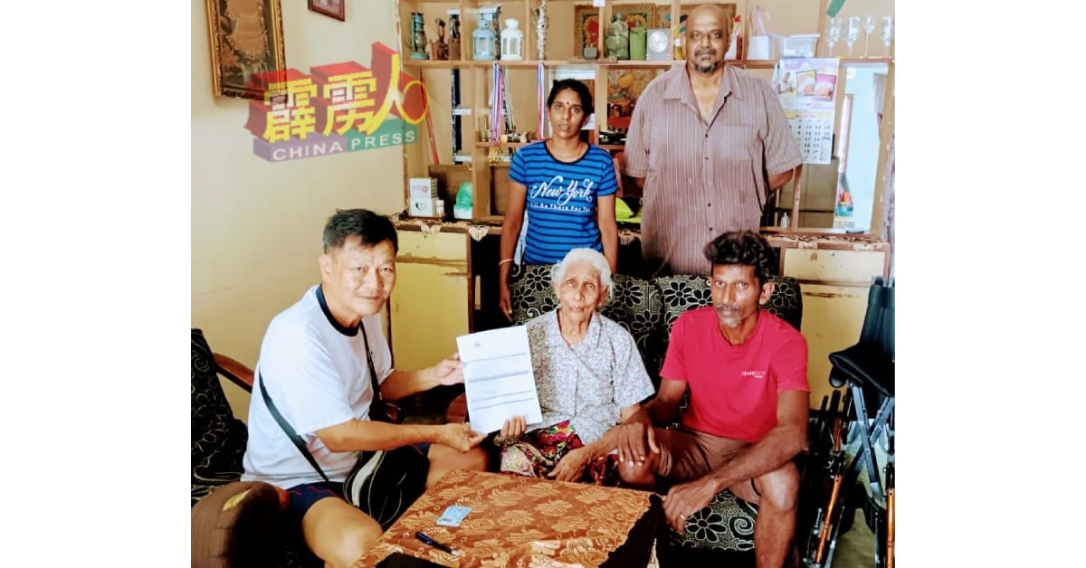 茹汝光（左起）协助残障老妇亚咪儿达申请残疾卡；站者右为慕鲁卡亚。