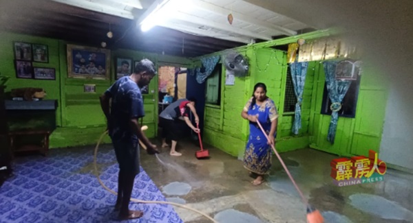 水位退下后，灾民忙于清洗屋内留下的污泥。 