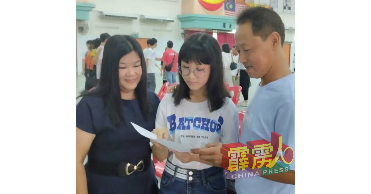 许紫怡（中）拿着SPM成绩单与父亲许国生（右）和母亲何秀香分享喜悦。
