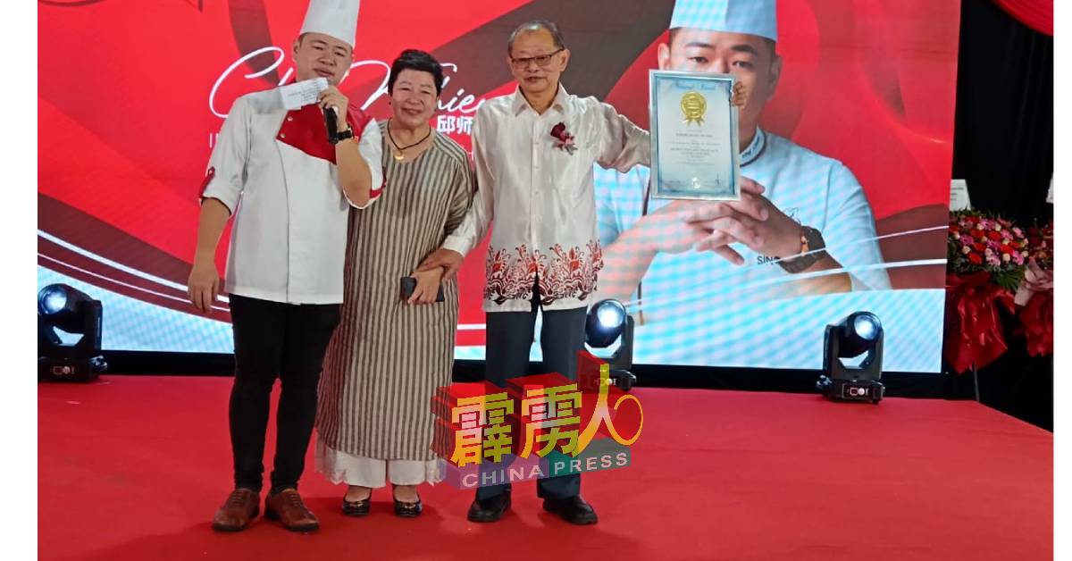 邱师傅（左）将马来西亚2023年度盆菜网络销售额最高记录荣誉，当作父亲节礼物赠送给慈父邱涌资（右），中为母亲杨紫凤。