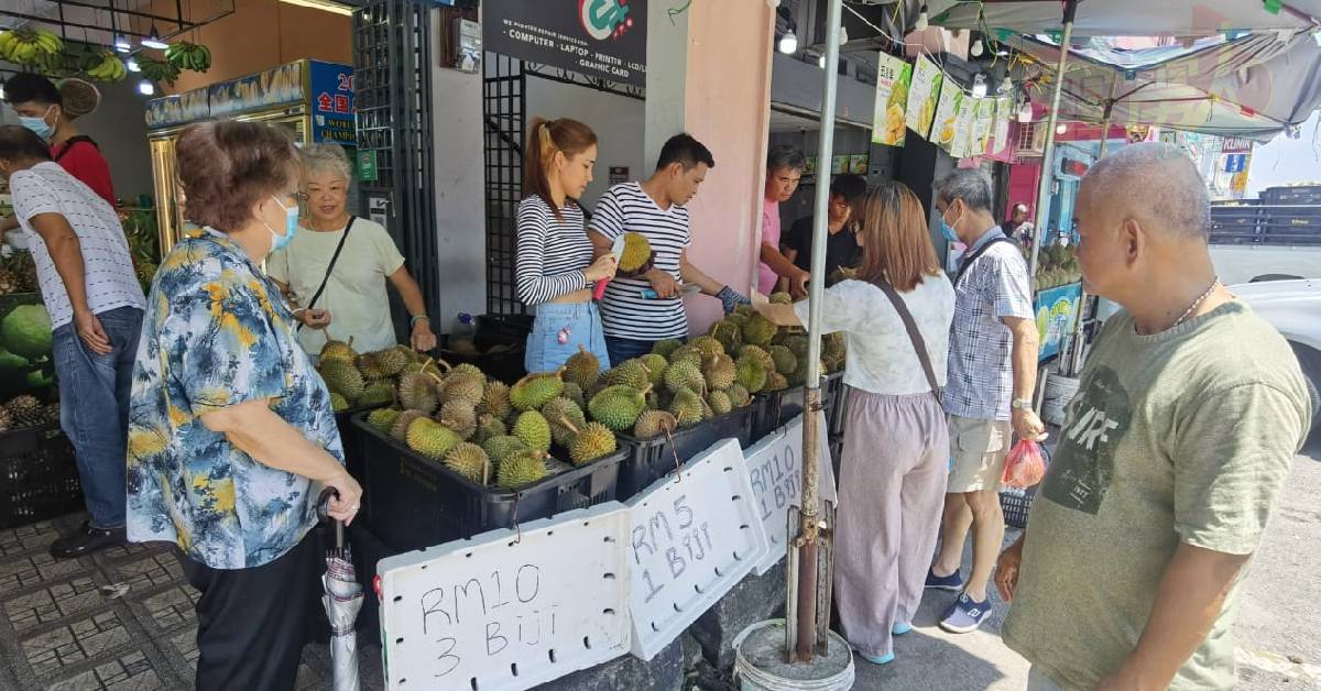 本地榴梿丰收且价格廉宜，不少市民围在摊前选购。