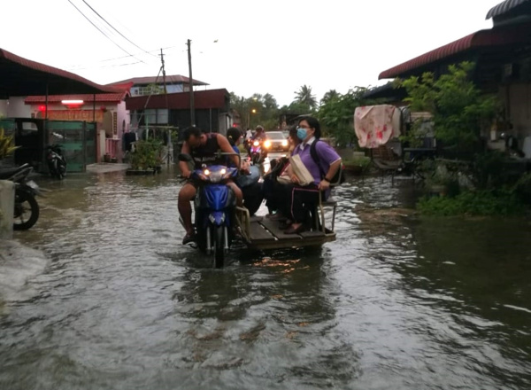 村民在大路淹水时，动用摩哆载送代步。